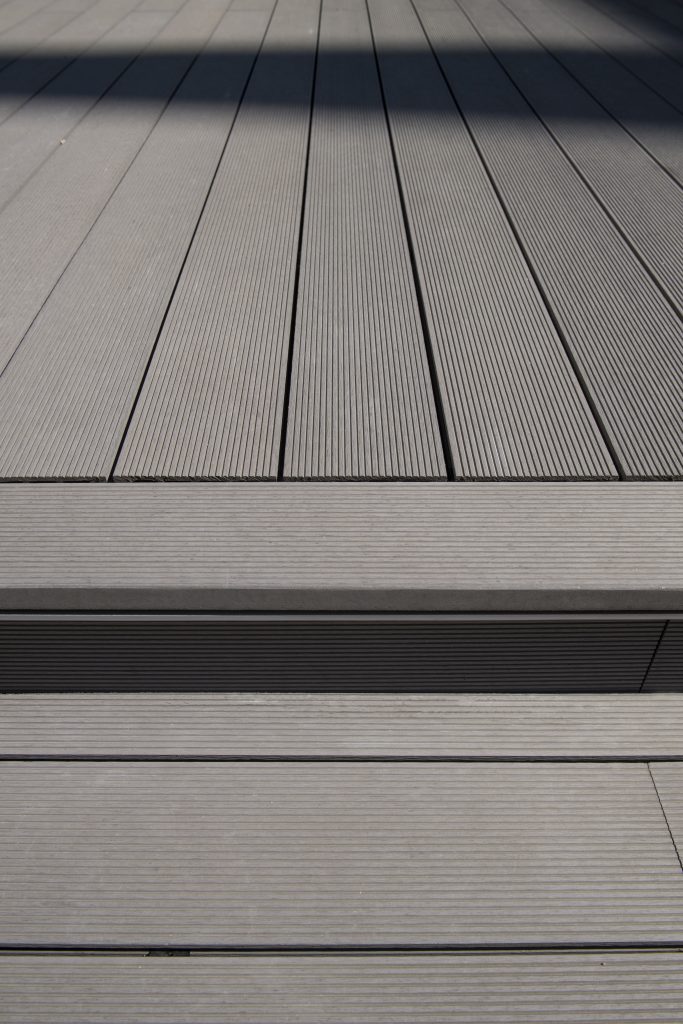 Gros plan sur une terrasse en bois composite LAMEO - lame XTRA coloris béton face striée